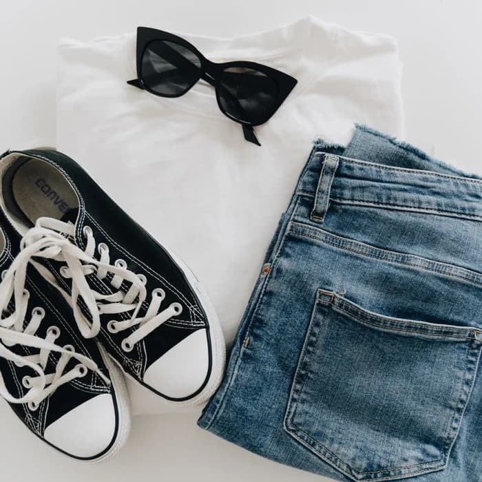 One photo of an outfit laid out flat: t-shirt, jeans, sneakers and sunglasses
